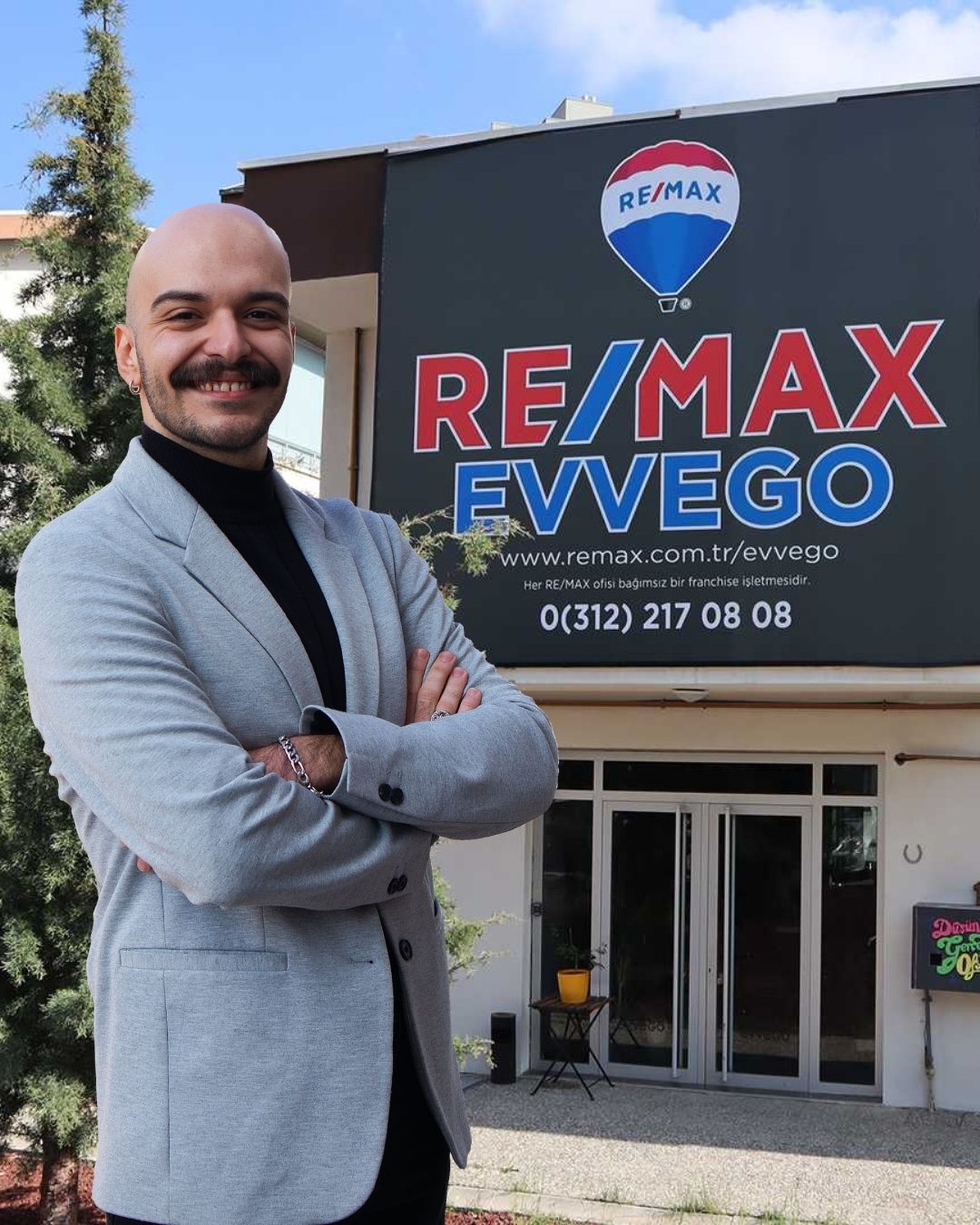 Ofisi önünde poz vermiş bir gayrimenkul danışmanı.