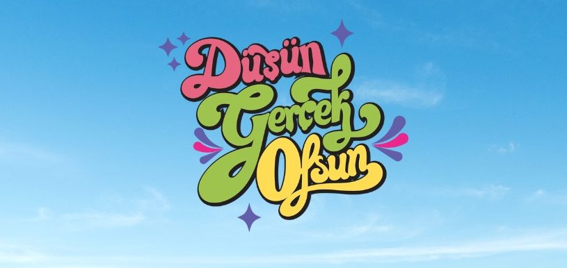 Mavi gökyüzü üzerinde renkli tipografi ile yazılmış 'Düşün Gerçek Olsun' motivasyon mesajı.